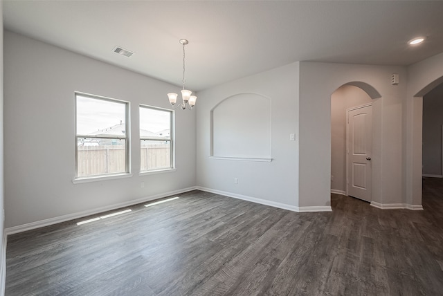 spare room featuring a notable chandelier and dark wood-type flooring