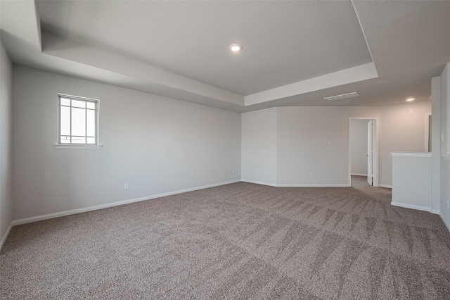 carpeted empty room with a raised ceiling