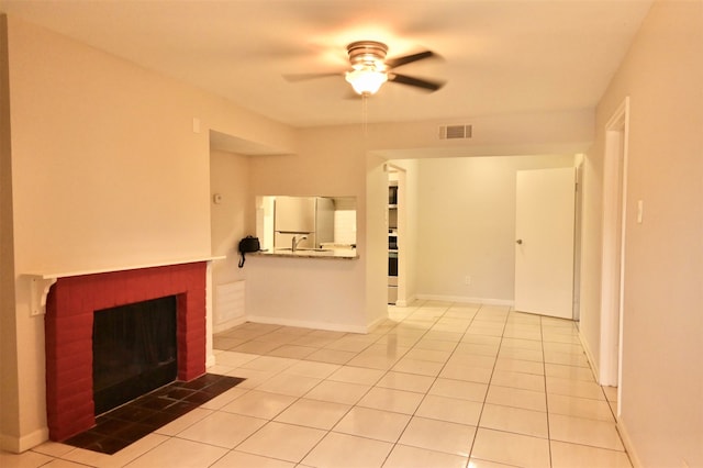 unfurnished living room featuring ceiling fan, a fireplace, sink, and light tile patterned floors