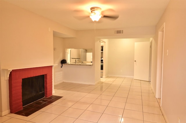 unfurnished living room featuring ceiling fan, a brick fireplace, and light tile patterned flooring