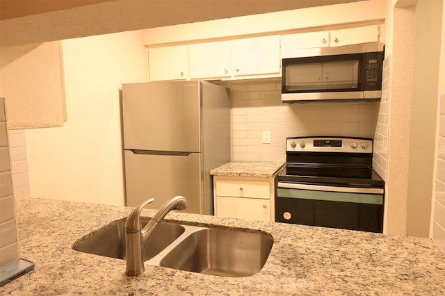 kitchen with sink, decorative backsplash, light stone counters, white cabinetry, and stainless steel appliances