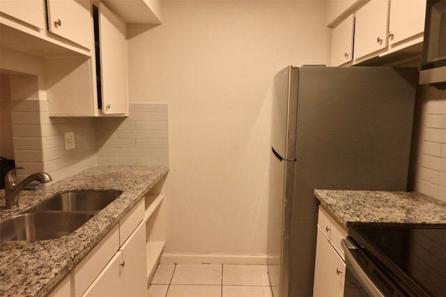 kitchen with backsplash, white cabinetry, sink, light stone counters, and light tile patterned flooring