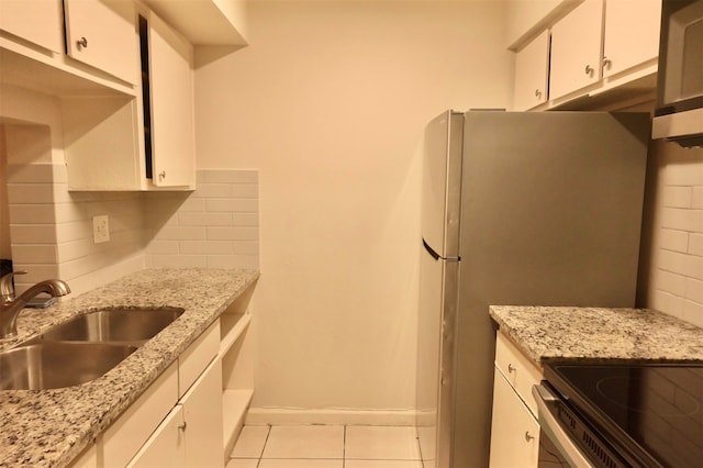 kitchen with decorative backsplash, sink, light stone countertops, white cabinets, and light tile patterned floors