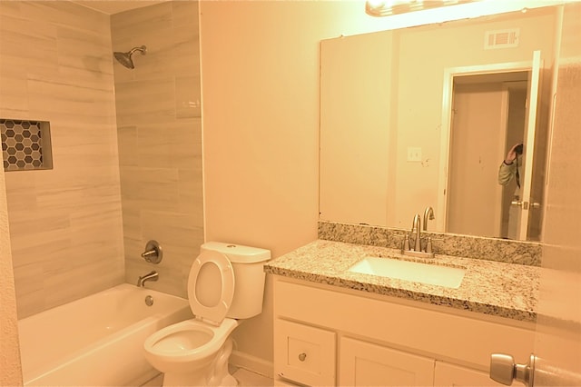 full bathroom featuring tiled shower / bath, vanity, and toilet