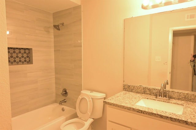 full bathroom featuring tiled shower / bath combo, toilet, and vanity