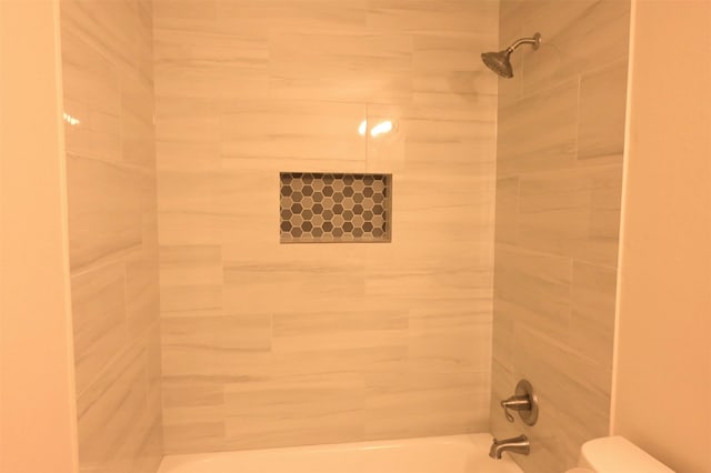 bathroom featuring toilet and tiled shower / bath combo