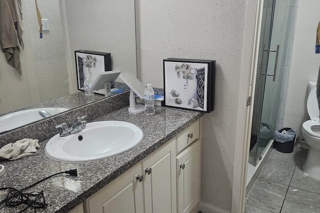 bathroom with tile patterned floors, a shower with door, vanity, and toilet