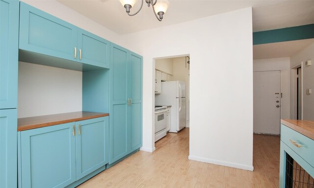 kitchen with blue cabinetry, light wood-type flooring, white appliances, and a notable chandelier