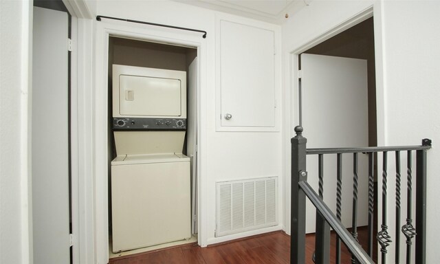 laundry area featuring dark hardwood / wood-style flooring and stacked washer and dryer