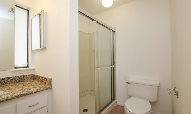 bathroom featuring vanity, toilet, and a shower with shower door