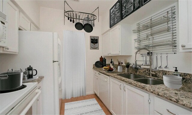 kitchen with white cabinetry, sink, light stone counters, light hardwood / wood-style flooring, and white appliances