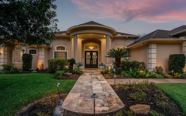 exterior entry at dusk featuring a yard and french doors