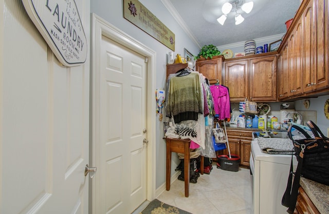 clothes washing area with cabinets, crown molding, a textured ceiling, washer / dryer, and light tile patterned flooring