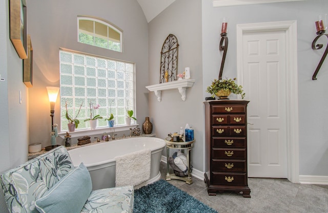 bathroom featuring a washtub and lofted ceiling