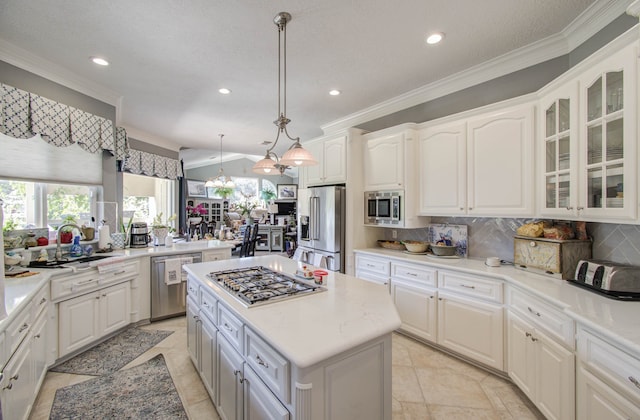 kitchen featuring pendant lighting, white cabinets, ornamental molding, a kitchen island, and stainless steel appliances