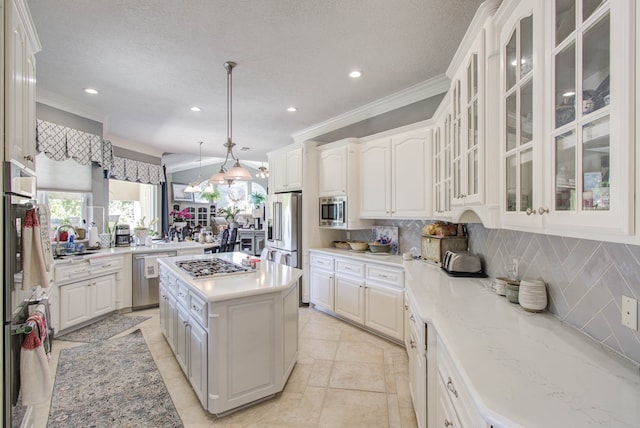 kitchen with a center island, hanging light fixtures, ornamental molding, white cabinetry, and stainless steel appliances