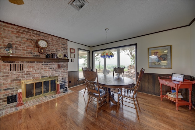 dining space with wood walls, hardwood / wood-style floors, a textured ceiling, and a fireplace