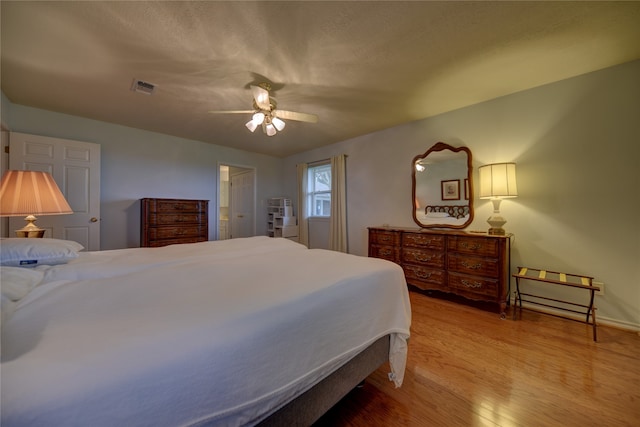 bedroom featuring ceiling fan, wood-type flooring, and a textured ceiling