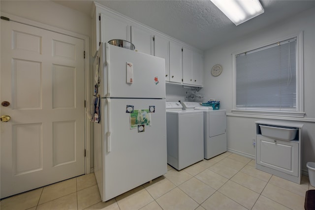 laundry area with light tile patterned flooring, independent washer and dryer, a textured ceiling, and cabinets