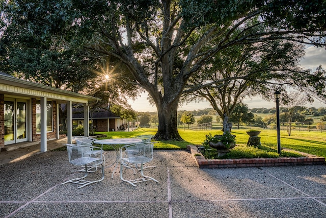 yard at dusk featuring a rural view and a patio area