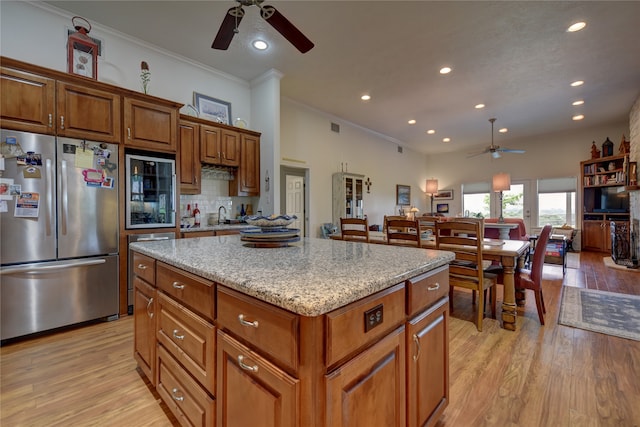 kitchen featuring light stone counters, tasteful backsplash, a center island, light hardwood / wood-style flooring, and stainless steel refrigerator