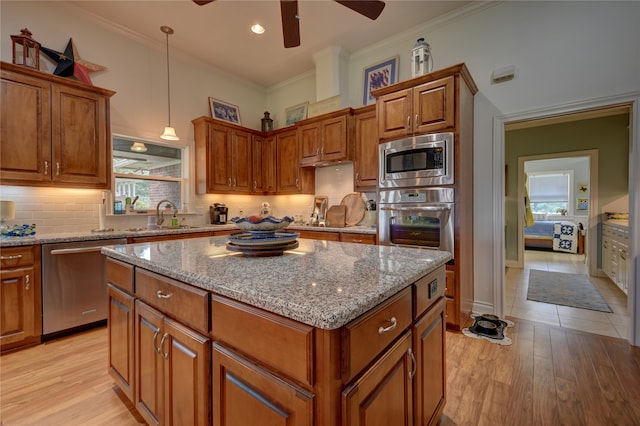 kitchen featuring a kitchen island, light hardwood / wood-style flooring, ornamental molding, decorative light fixtures, and appliances with stainless steel finishes