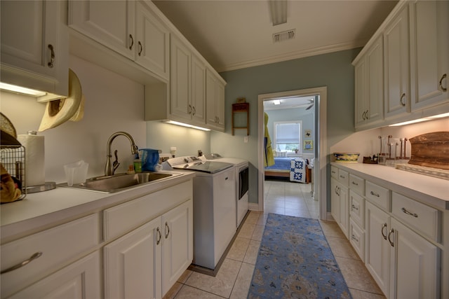 kitchen featuring washing machine and clothes dryer, light tile patterned floors, sink, and white cabinets