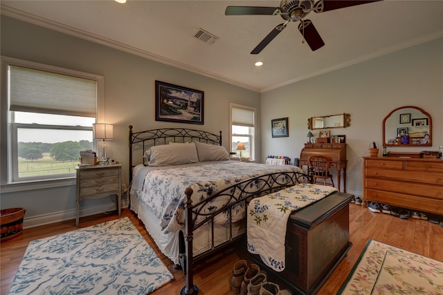 bedroom featuring crown molding, ceiling fan, hardwood / wood-style floors, and multiple windows