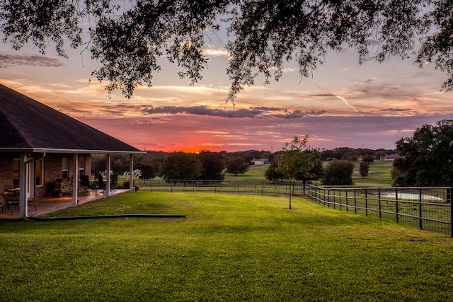 yard at dusk with a rural view and a patio area