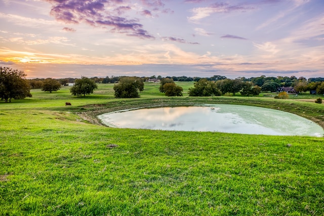 surrounding community with a water view and a yard