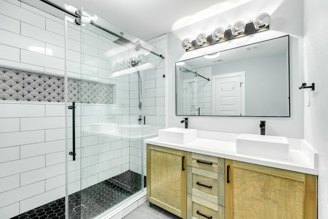 bathroom featuring a shower with door, tile patterned flooring, and dual bowl vanity