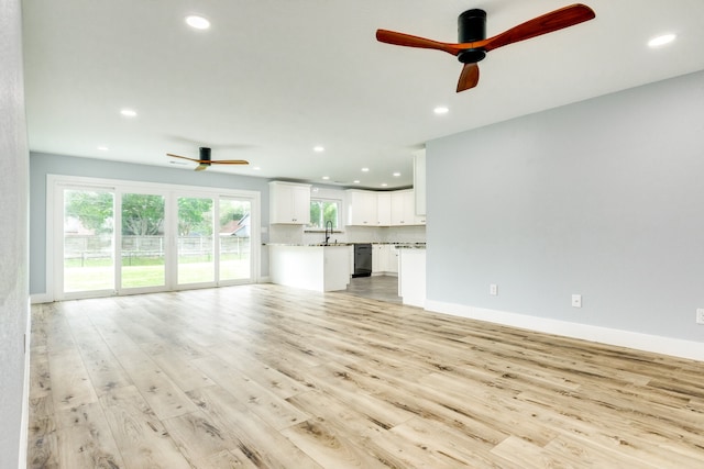 unfurnished living room featuring sink, light hardwood / wood-style flooring, and ceiling fan