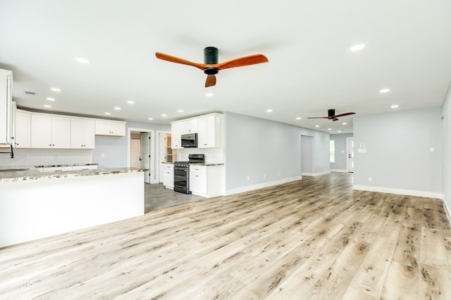 unfurnished living room with sink, light wood-type flooring, and ceiling fan