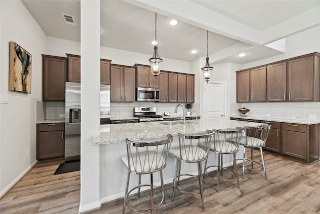 kitchen featuring sink, appliances with stainless steel finishes, light wood-type flooring, and tasteful backsplash