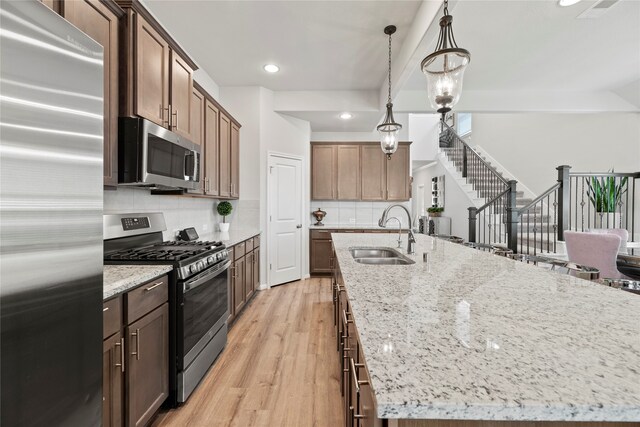 kitchen with sink, decorative backsplash, appliances with stainless steel finishes, and light wood-type flooring