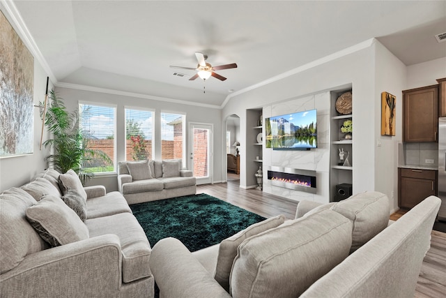 living room with crown molding, light wood-type flooring, and a large fireplace