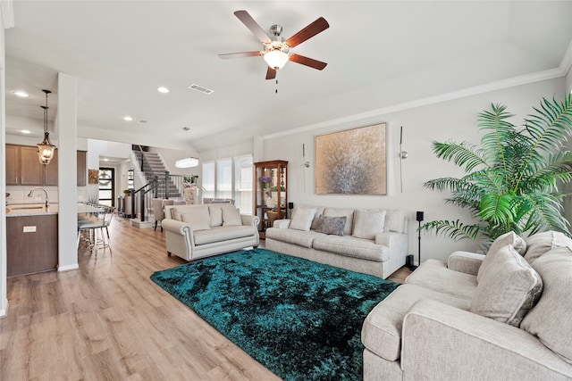 living room with ornamental molding, sink, light hardwood / wood-style flooring, and ceiling fan