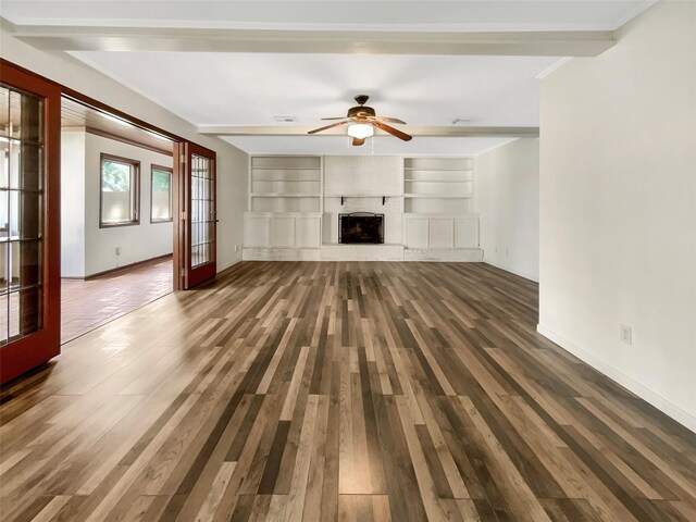 unfurnished living room with built in features, wood-type flooring, ceiling fan, and french doors