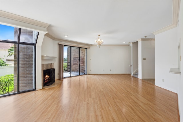 unfurnished living room featuring a premium fireplace, crown molding, a chandelier, and light wood-type flooring