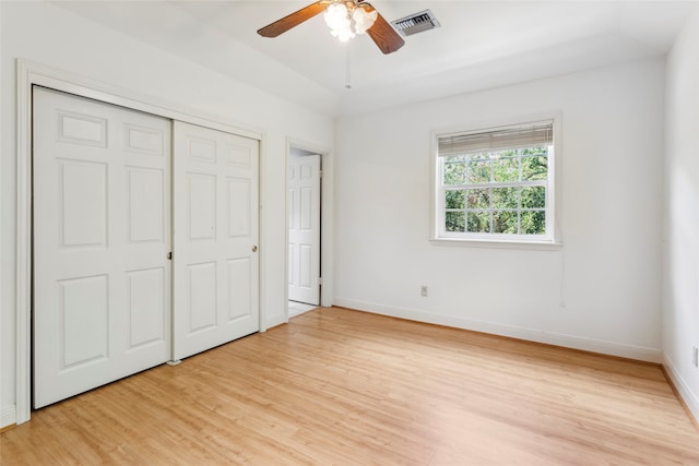 unfurnished bedroom featuring vaulted ceiling, a closet, ceiling fan, and light wood-type flooring