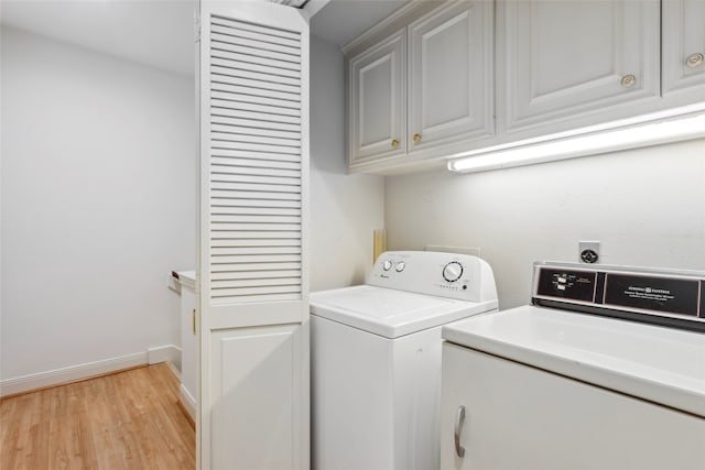 clothes washing area with cabinets, separate washer and dryer, and light hardwood / wood-style floors