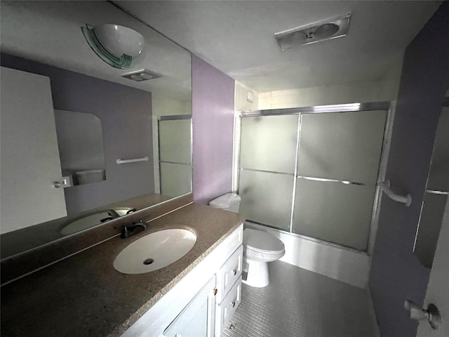 full bathroom featuring enclosed tub / shower combo, vanity, and toilet