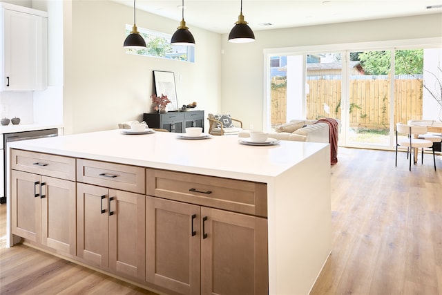 kitchen with white cabinets, decorative light fixtures, and light wood-type flooring