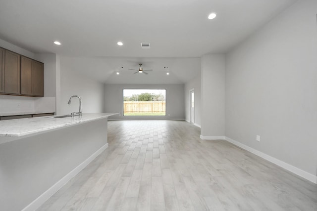 interior space with light wood-type flooring, ceiling fan, lofted ceiling, and sink