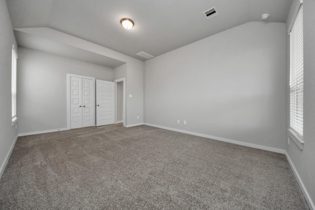 unfurnished bedroom featuring carpet, vaulted ceiling, and a closet