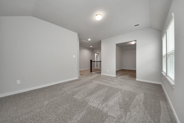 spare room featuring carpet flooring and lofted ceiling