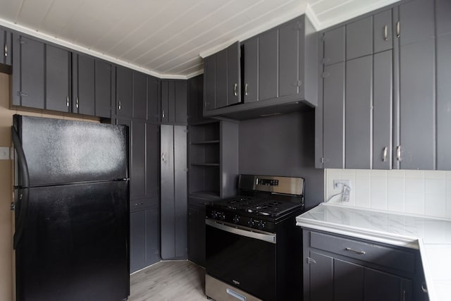 kitchen with black fridge, gray cabinetry, stainless steel range with gas cooktop, and light hardwood / wood-style flooring