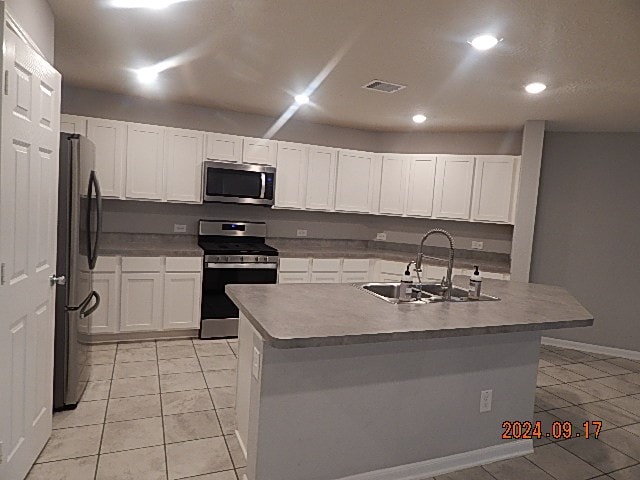 kitchen with white cabinets, a kitchen island with sink, appliances with stainless steel finishes, and sink