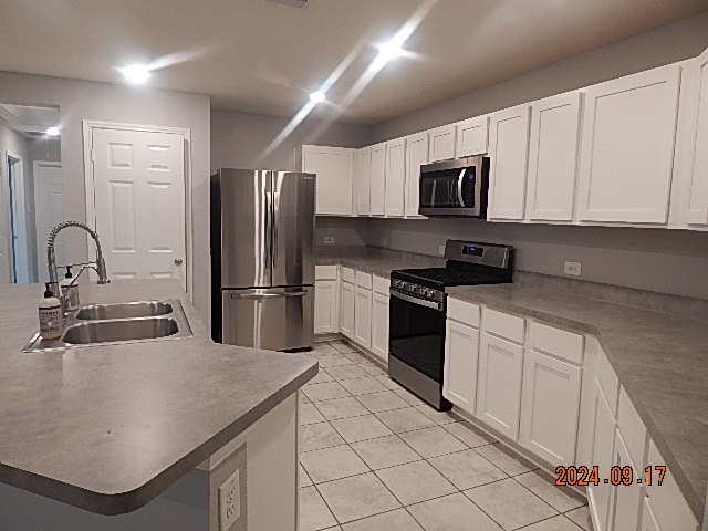 kitchen featuring light tile patterned floors, appliances with stainless steel finishes, sink, and white cabinetry