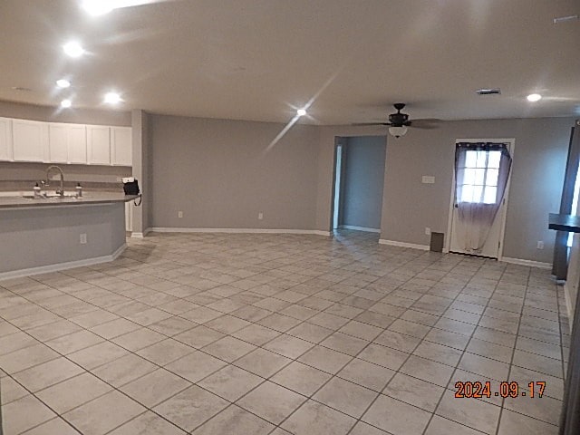 unfurnished living room featuring sink and ceiling fan